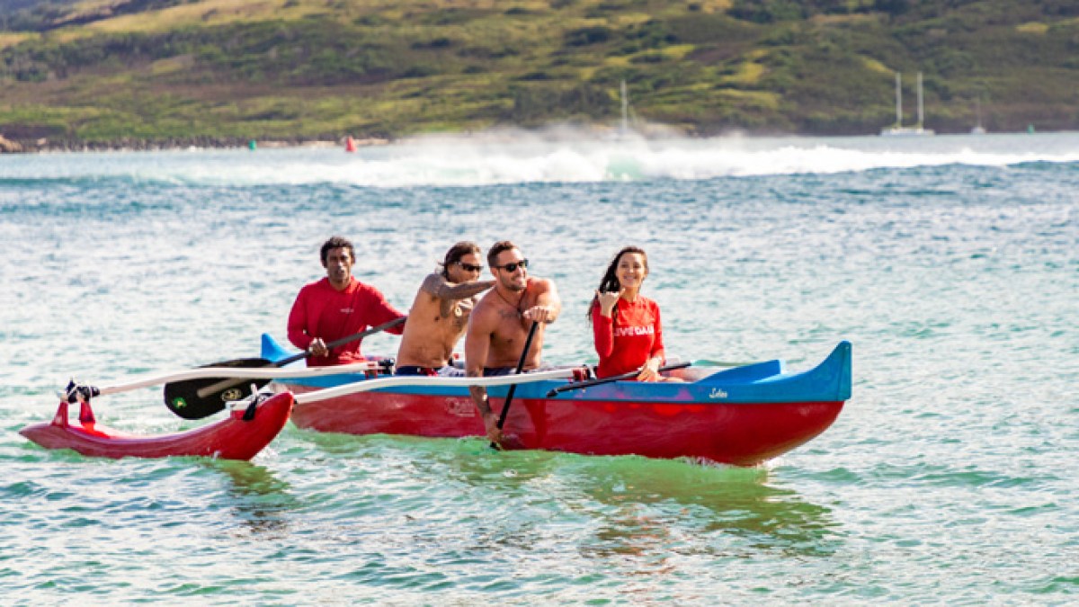 a group of people riding on the back of a boat in the water