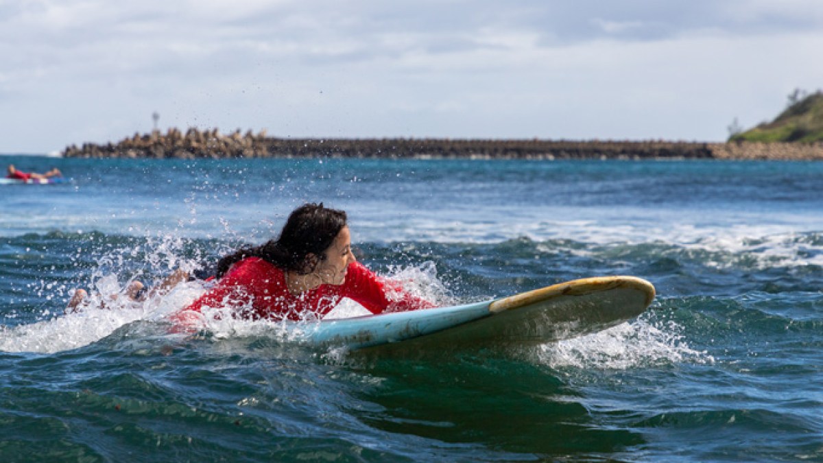 a small girl riding a wave on a surfboard in the water